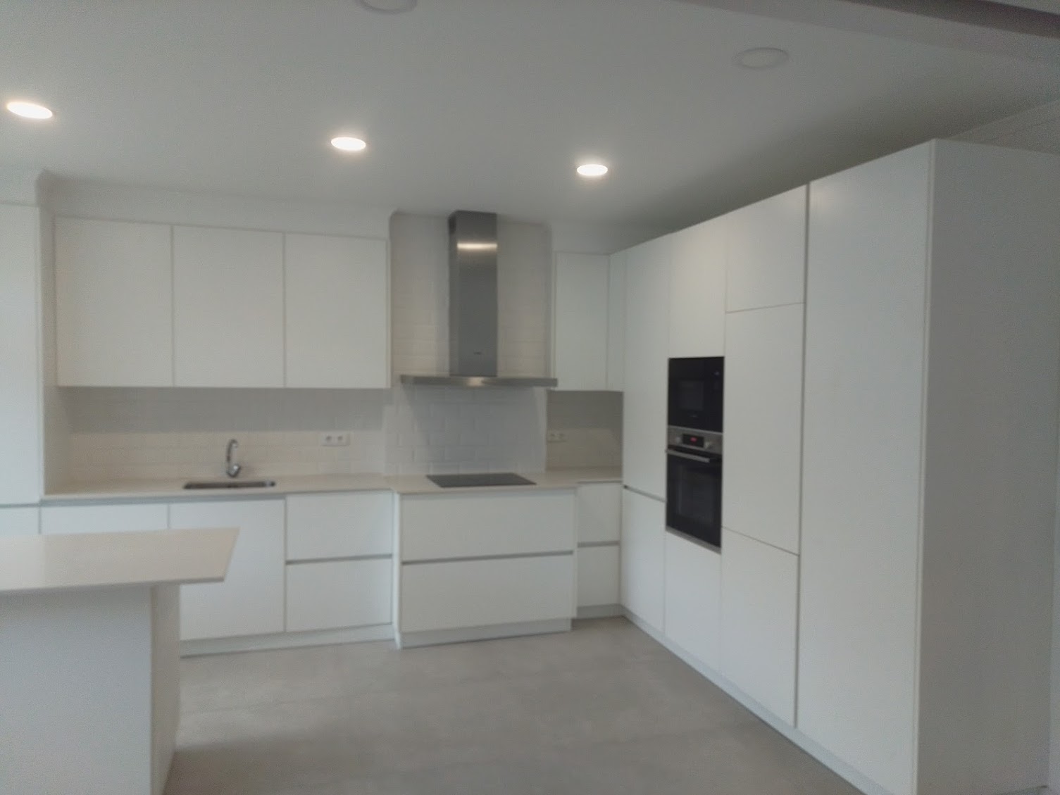 Cozinha moderna lacada a branco com forno e exaustor inox